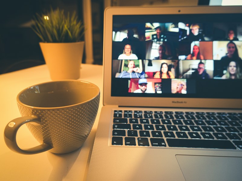 Laptop showing a video call beside a mug of coffee