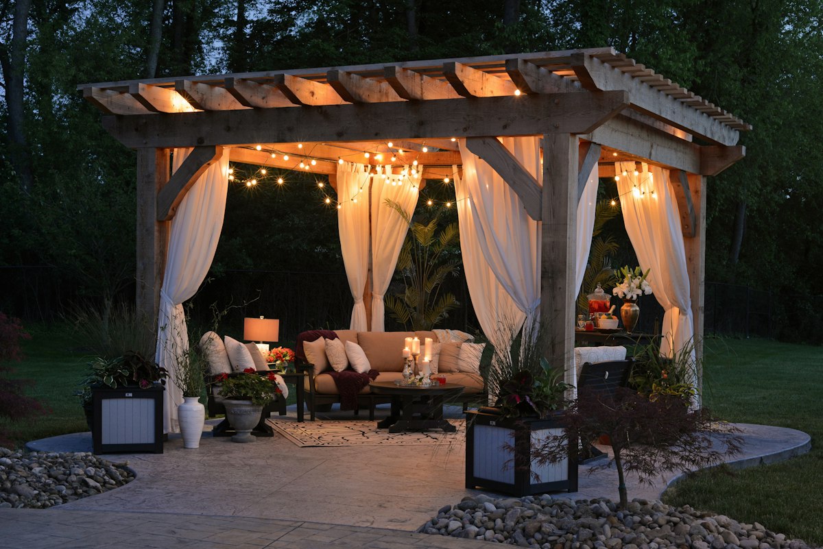 Garden gazebo with flowing curtains and string lights glowing at dusk