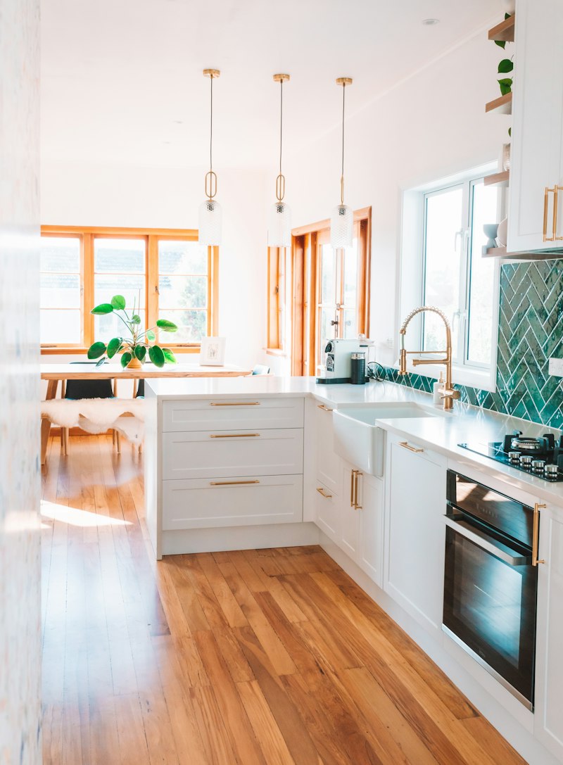 Bright modern kitchen with white cabinets, wood floors and large windows
