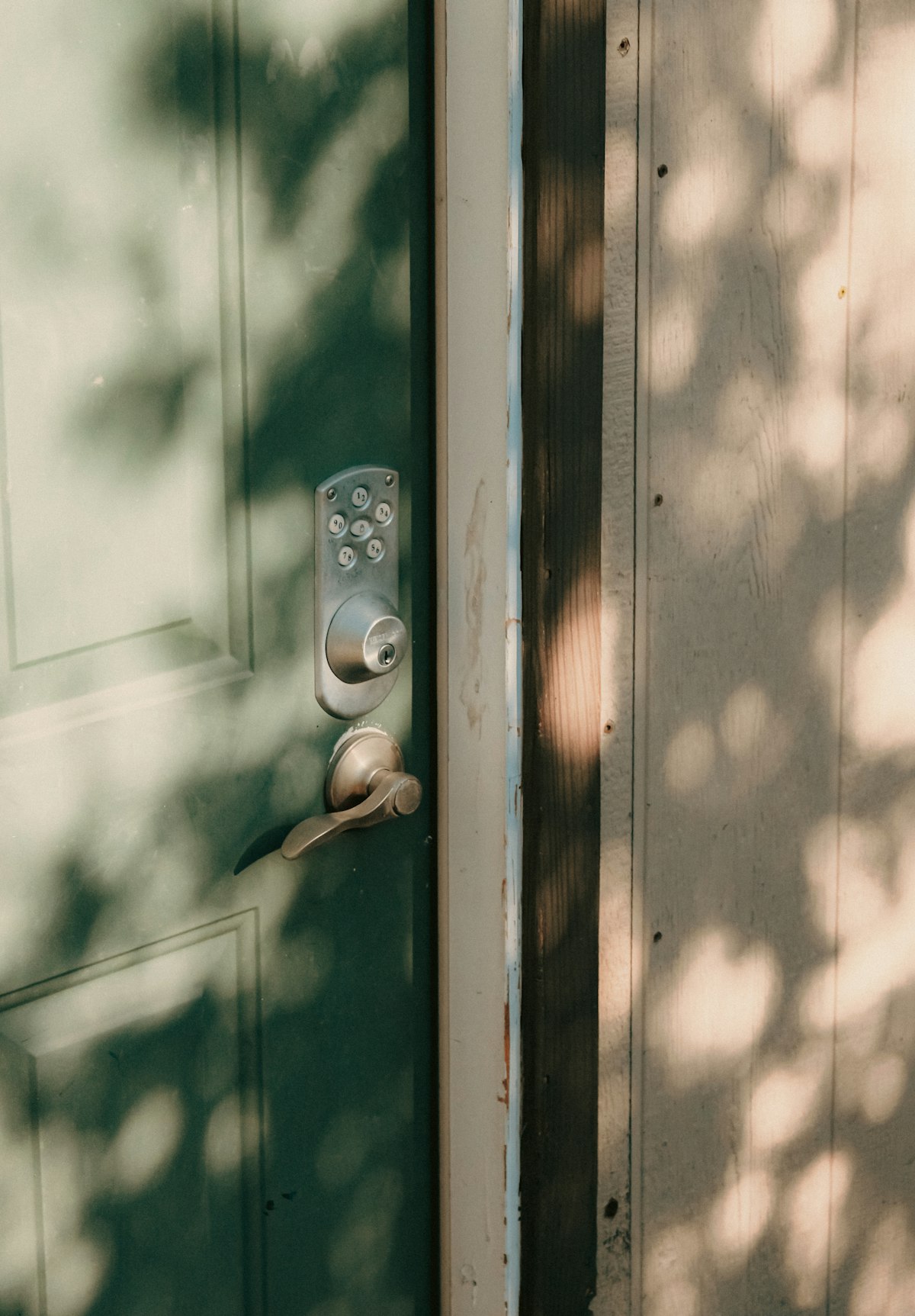 Smart keypad lock on a sunlit green front door