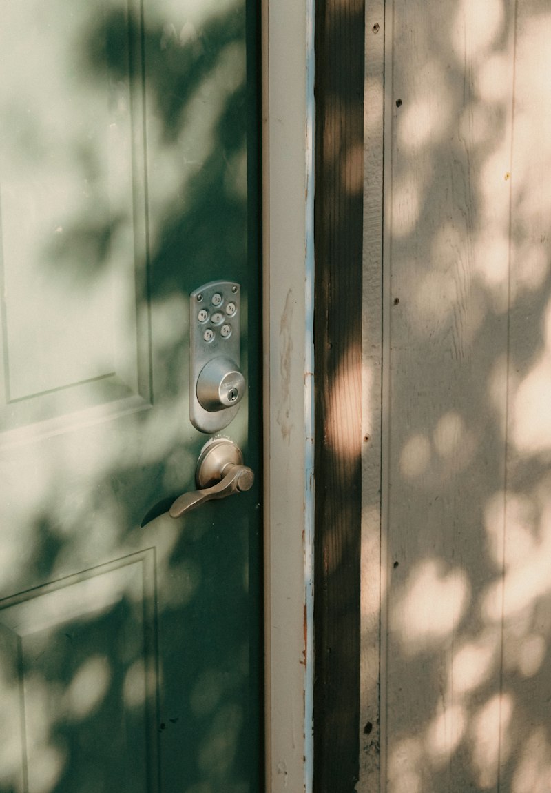 Smart keypad lock on a sunlit green front door